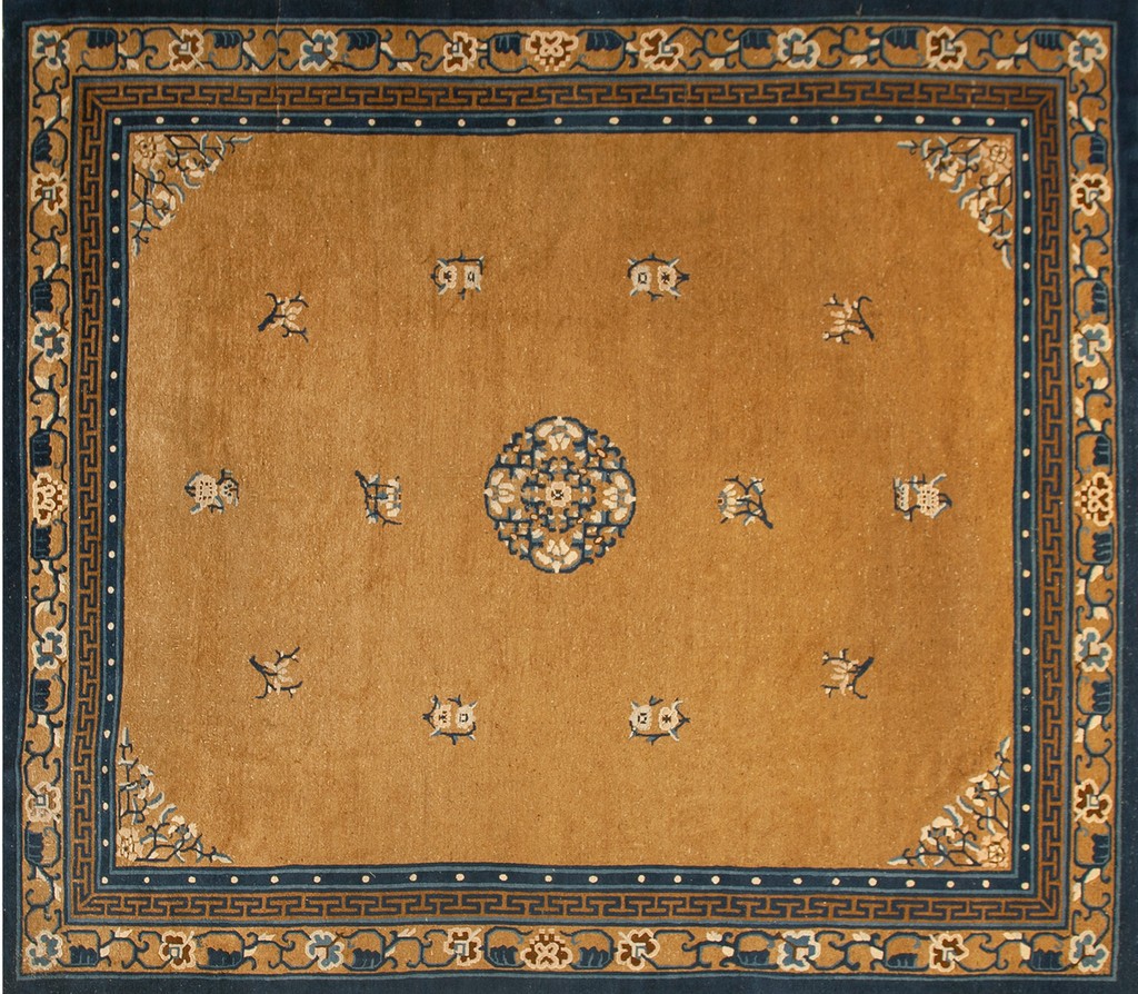 A rectangular antique chinese wool rug with a dominant golden-mustard field, scattered light blue symbolic motifs, and a dark indigo border featuring geometric and floral patterns, by rugs on net.