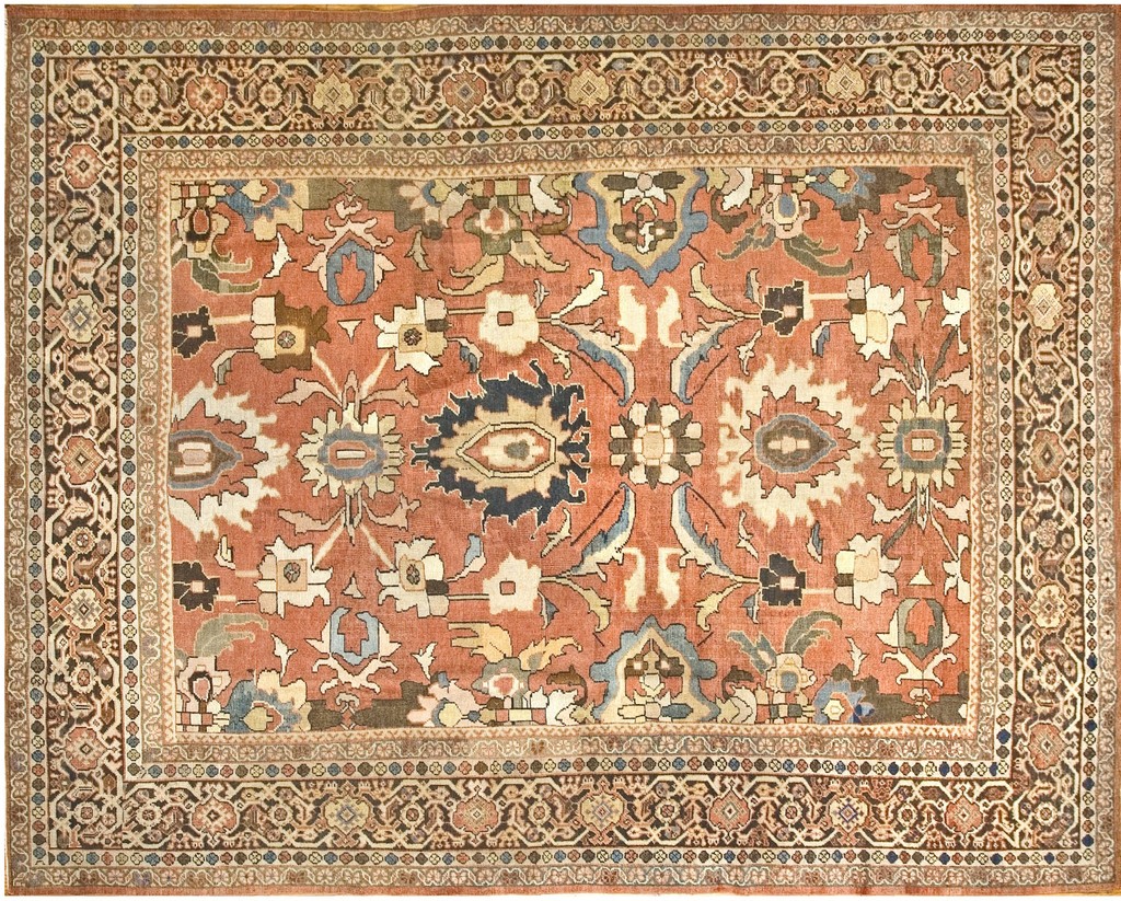 An antique persian sultanabad rug with a large-scale, open design featuring stylized floral motifs in coral, indigo, cream, and brown, framed by an intricate geometric border. Swastika  design by rugs on net