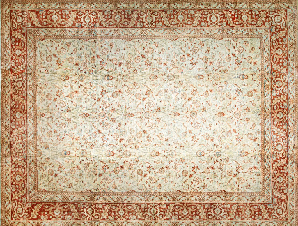 An antique rectangular persian tabriz rug with a light ivory central field covered in small, scattered rust-colored floral sprigs, enclosed by a wide, ornate border featuring detailed scrolling red and ivory patterns, by rugs on net.