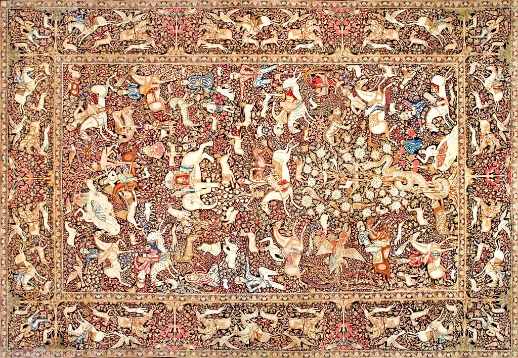 A highly detailed, antique persian kerman rug featuring a dense, all-over pictorial hunting scene with figures on horseback battling animals amidst dense floral motifs, bordered by narrower hunting vignettes by rugs on net.