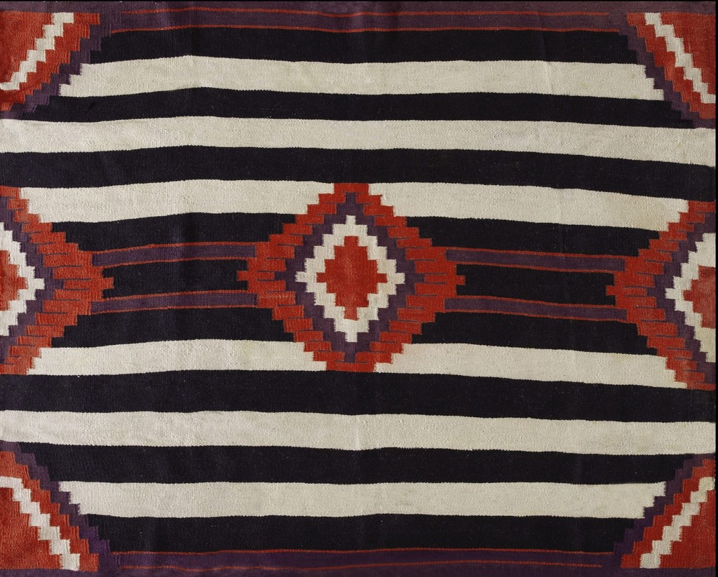 Close-up view of an antique native american flatwoven rug with thick horizontal stripes of black and cream, featuring central diamond shapes in red and purple, by rugs on net.