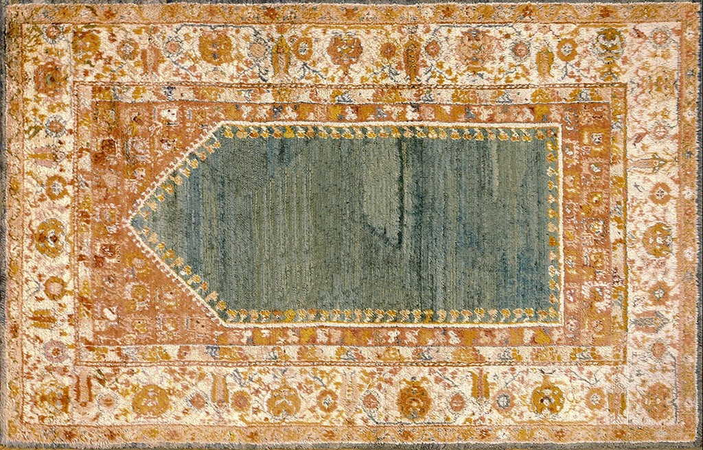 Islamic rugs - an antique oushak rug featuring a central, vertically-striped angora blue prayer niche framed by wide borders in rust, cream, and gold floral patterns by rugs on net.