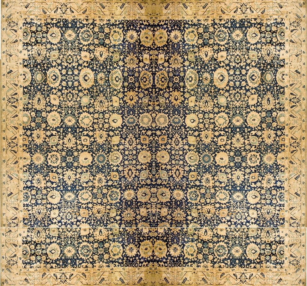 An antique oversized wool agra rug featuring an all-over repeating floral design in deep navy blue and aged ivory with a wide, patterned border by rugs on net.