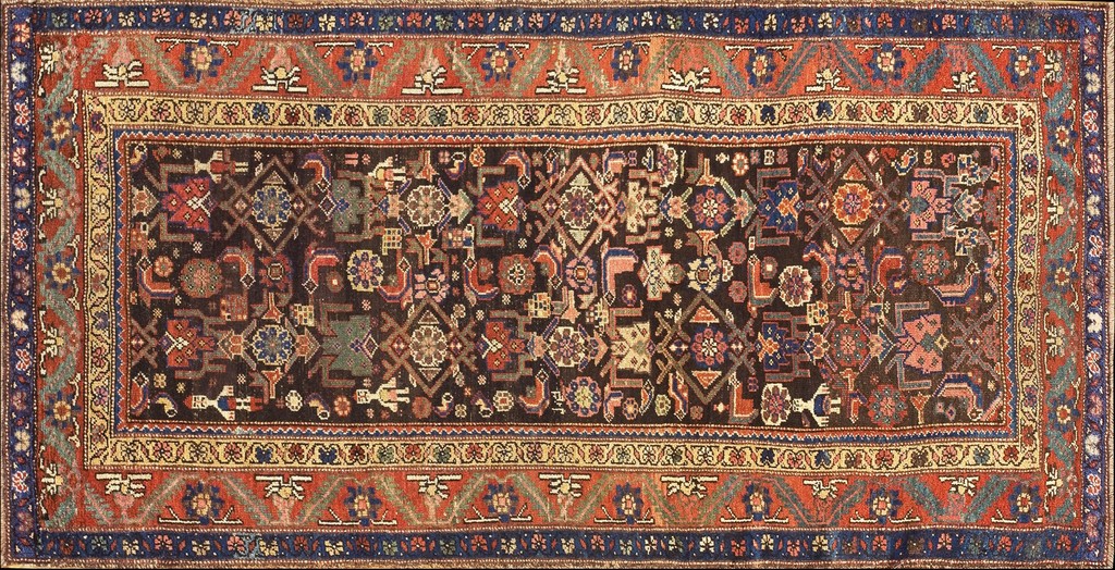 A rectangular antique persian wool rug with a dark brown allover geometric field bordered by red, cream, and navy blue bands, by rugs on net.