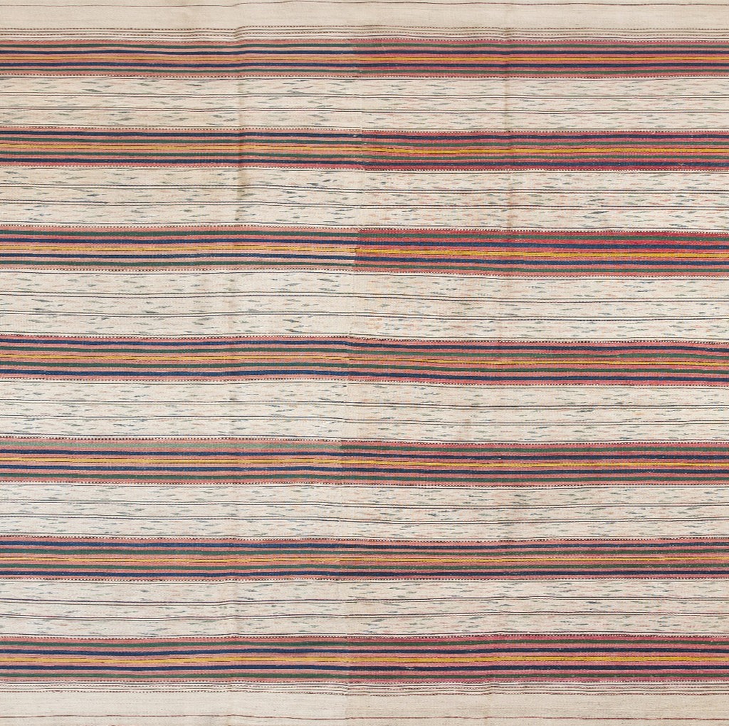 A close-up view of a flat-woven turkish kilim rug featuring numerous horizontal stripes in cream, indigo, terracotta, and gold over an off-white field by rugs on net.