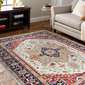 Red and ivory traditional area rug beneath a green velvet sofa on light hardwood flooring.