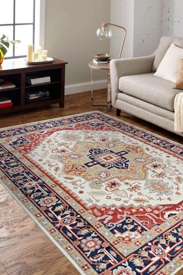 Red and ivory traditional area rug beneath a green velvet sofa on light hardwood flooring.