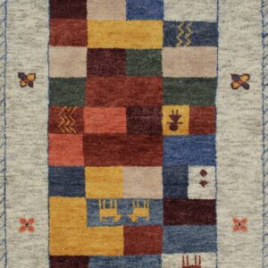 Beige rug with stylized figures and a multi-colored geometric border, folded on wood plank flooring.