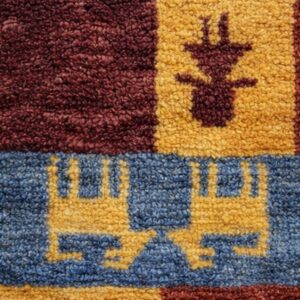 Beige abrash rug featuring naive red and white animal motifs and a thick geometric border, folded on light wood floor.