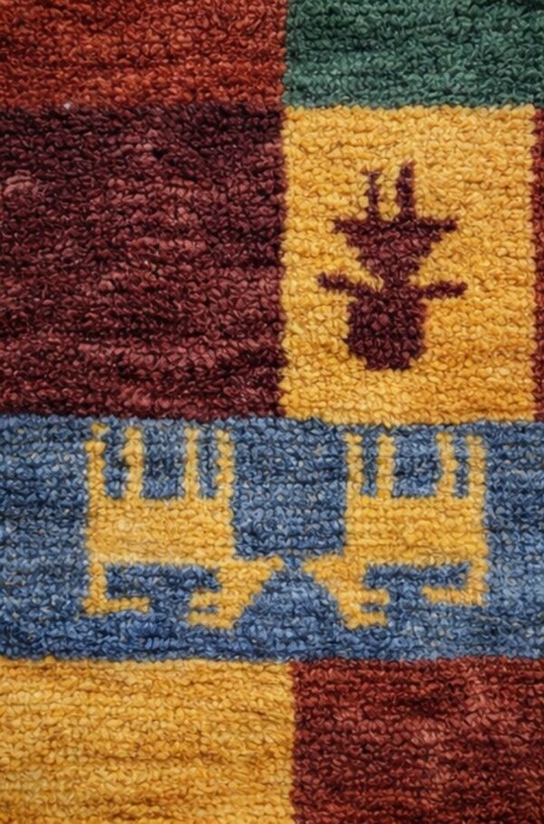 Beige abrash rug featuring naive red and white animal motifs and a thick geometric border, folded on light wood floor.