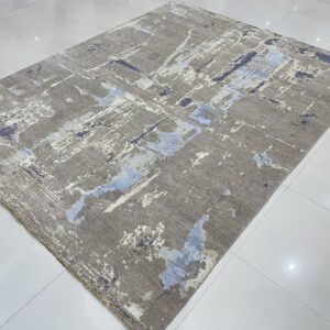 Abstract gray rug with blue and cream accents displayed on glossy white square tile.