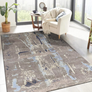 Abstract taupe rug with streaks of light and dark blue anchors a cream armchair by large windows.