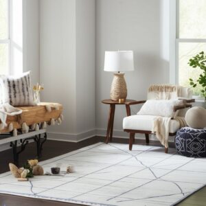 Light white rug with gray diagonal lines under a beige tufted sofa on dark wood flooring.