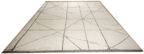 Large cream rug with light gray geometric intersecting lines and decorative tassels on a wood floor.