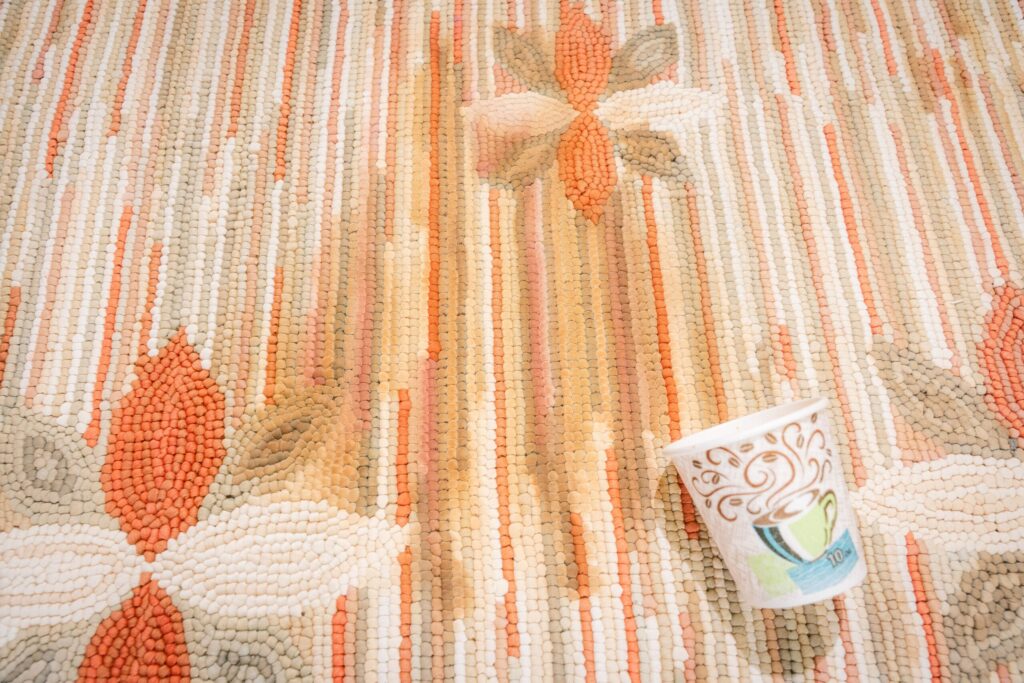Close-up of a spilled coffee cup on a traditional handwoven wool rug with geometric motifs. By rugs on net