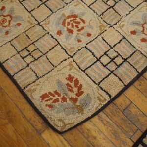 Close-up of a hooked rug with geometric and floral motifs in beige, rust, and blue, resting on wood floors, by Rugs On Net