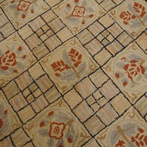 Close-up of a beige rug with repeating burnt orange floral medallions and a grid pattern by Rugs On Net. by Rugs On Net