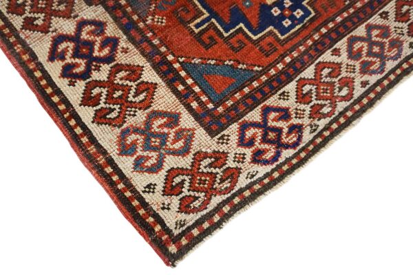 Close-up corner detail of a caucasian rug with geometric red and blue motifs by rugs on net