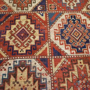 Close-up of geometric medallions on a red and blue antique rug by Rugs On Net