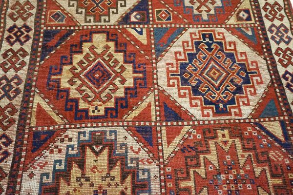 Close-up of geometric medallions on a red and blue antique rug by rugs on net