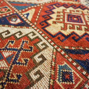 Close-up of geometric patterns in red, blue, and cream on a tribal rug by Rugs On Net. by Rugs On Net