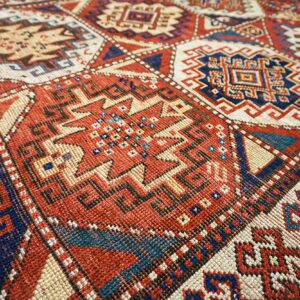 Close-up of geometric patterns on a red and blue Caucasian rug by Rugs On Net