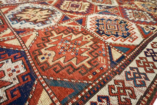 Close-up of geometric patterns on a red and blue caucasian rug by rugs on net