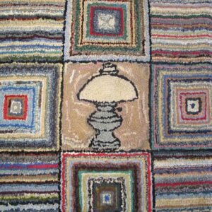 Close-up of a colorful hooked rug featuring squares and a central lamp motif, by Rugs On Net