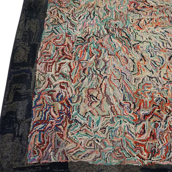 Close-up of a brightly colored, abstract patterned rug, likely a hooked rug, resting on a dark rug, by rugs on net