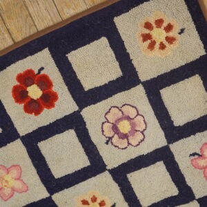 Close-up of a hooked rug featuring colorful flowers in light squares separated by navy borders, by Rugs On Net