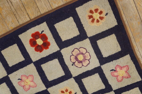Close-up of a hooked rug featuring colorful flowers in light squares separated by navy borders, by rugs on net