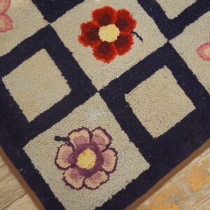 Close-up of a hooked rug with a navy blue grid pattern framing light squares, each containing a colorful flower, by Rugs On Net