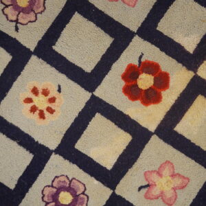 Close-up of a hooked rug featuring a light background, dark blue diamond lattice, and scattered colorful flowers, by Rugs On Net. by Rugs On Net