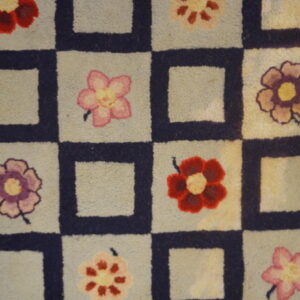 Close-up of a hooked rug with a checkerboard pattern featuring colorful flowers in the light squares, by Rugs On Net. by Rugs On Net