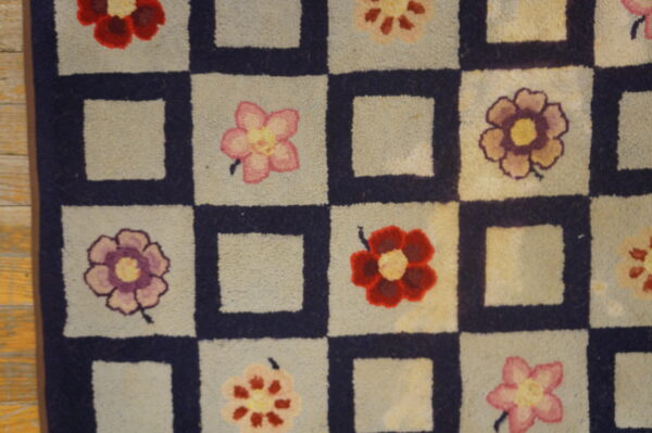 Close-up of a hooked rug with a checkerboard pattern featuring colorful flowers in the light squares, by rugs on net. By rugs on net