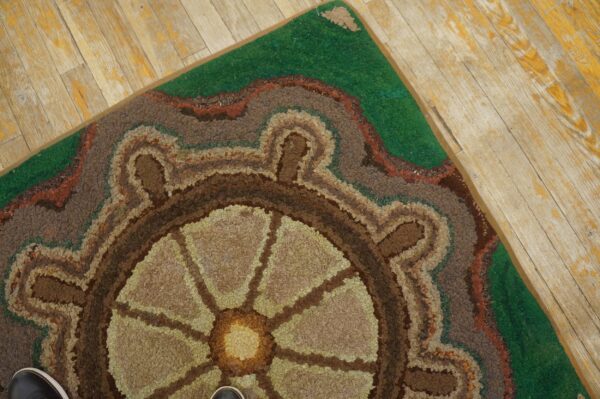 Close-up of a hooked rug featuring a ship's wheel design in earthy tones, by rugs on net. By rugs on net