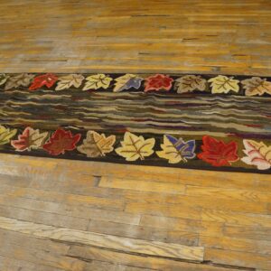 Hooked rug featuring colorful autumn leaves bordering wavy earth-toned center on wood floor by Rugs On Net
