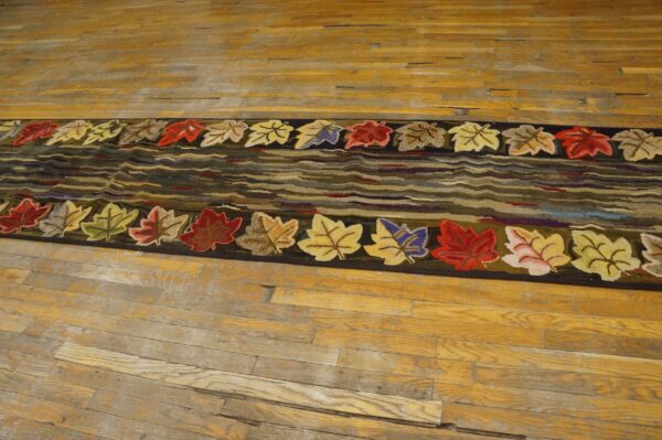 Hooked rug featuring colorful autumn leaves bordering wavy earth-toned center on wood floor by rugs on net