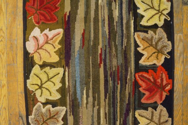Close-up of a hooked rug featuring colorful autumn leaves flanking a vertical striped center, by rugs on net