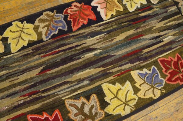 Close-up of a hooked rug featuring diagonal stripes and colorful maple leaves along the border, by rugs on net