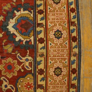 Close-up of the border and field of a richly colored, traditional rug featuring geometric and floral motifs in red, blue, and gold tones by Rugs On Net