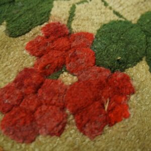 Close-up of a hooked rug featuring red floral elements on a tan background with green leaves, by Rugs On Net
