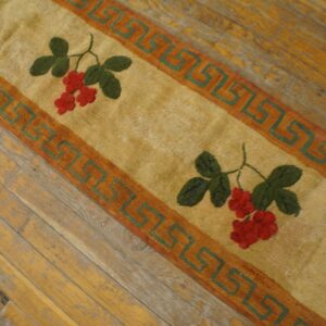A close-up of the Berry Pattern Rug showing red berries and green leaves on a tan field with a Greek key border, by Rugs On Net. by Rugs On Net