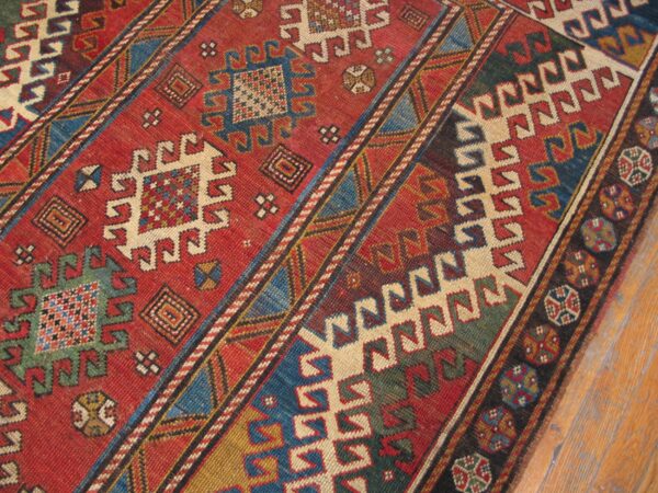 Close-up of a vibrant, geometric antique rug with red, blue, and cream motifs by rugs on net