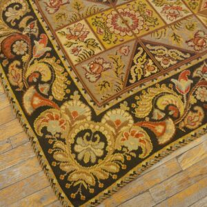 Close-up of a richly patterned, dark-bordered needlepoint rug on a worn wooden floor by Rugs On Net. by Rugs On Net