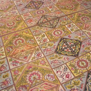Close-up of a colorful patchwork rug design featuring floral motifs in gold, red, and grey tones by Rugs On Net