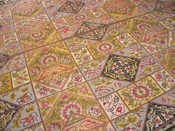 Close-up of a colorful patchwork rug design featuring floral motifs in gold, red, and grey tones by rugs on net