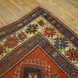 Close-up corner detail of a richly colored antique rug on a distressed wooden floor by Rugs On Net
