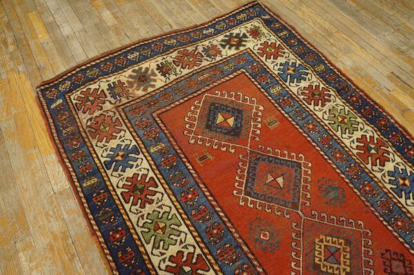 Close-up of a richly colored antique rug with geometric patterns on a distressed wooden floor by rugs on net. By rugs on net