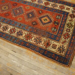 Close-up of a richly colored antique rug with geometric patterns in red and blue, resting on distressed wood floors, by Rugs On Net